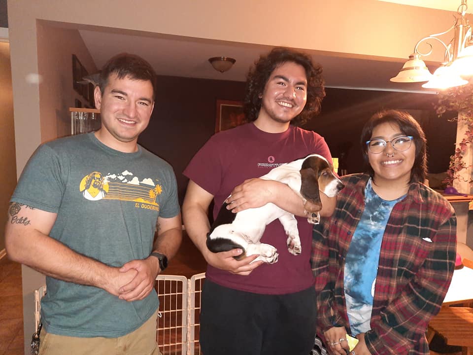 Two men and a woman are posing for a picture with a dog