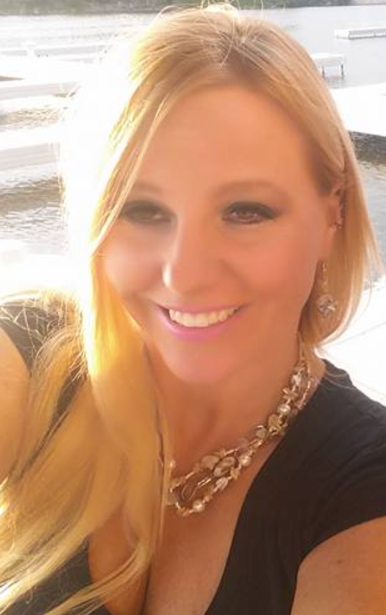 A woman wearing a necklace and earrings is smiling for the camera.