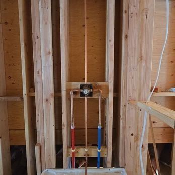 Copper pipes and valve assembly in wooden wall studs for a shower installation.