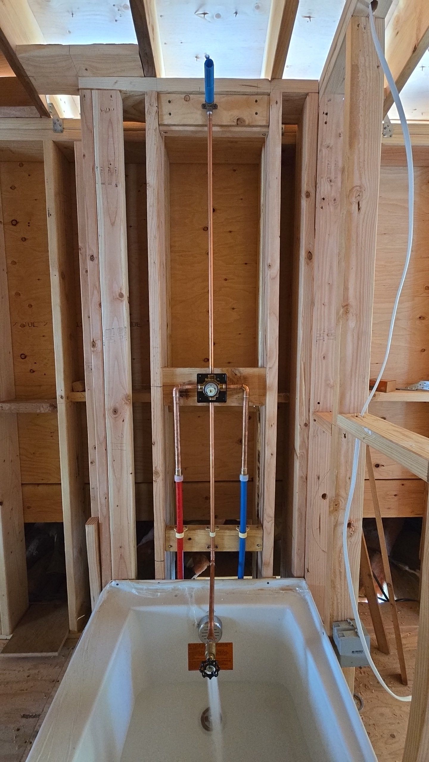 Copper pipes installed for a bathtub faucet and showerhead in a wooden framed wall.