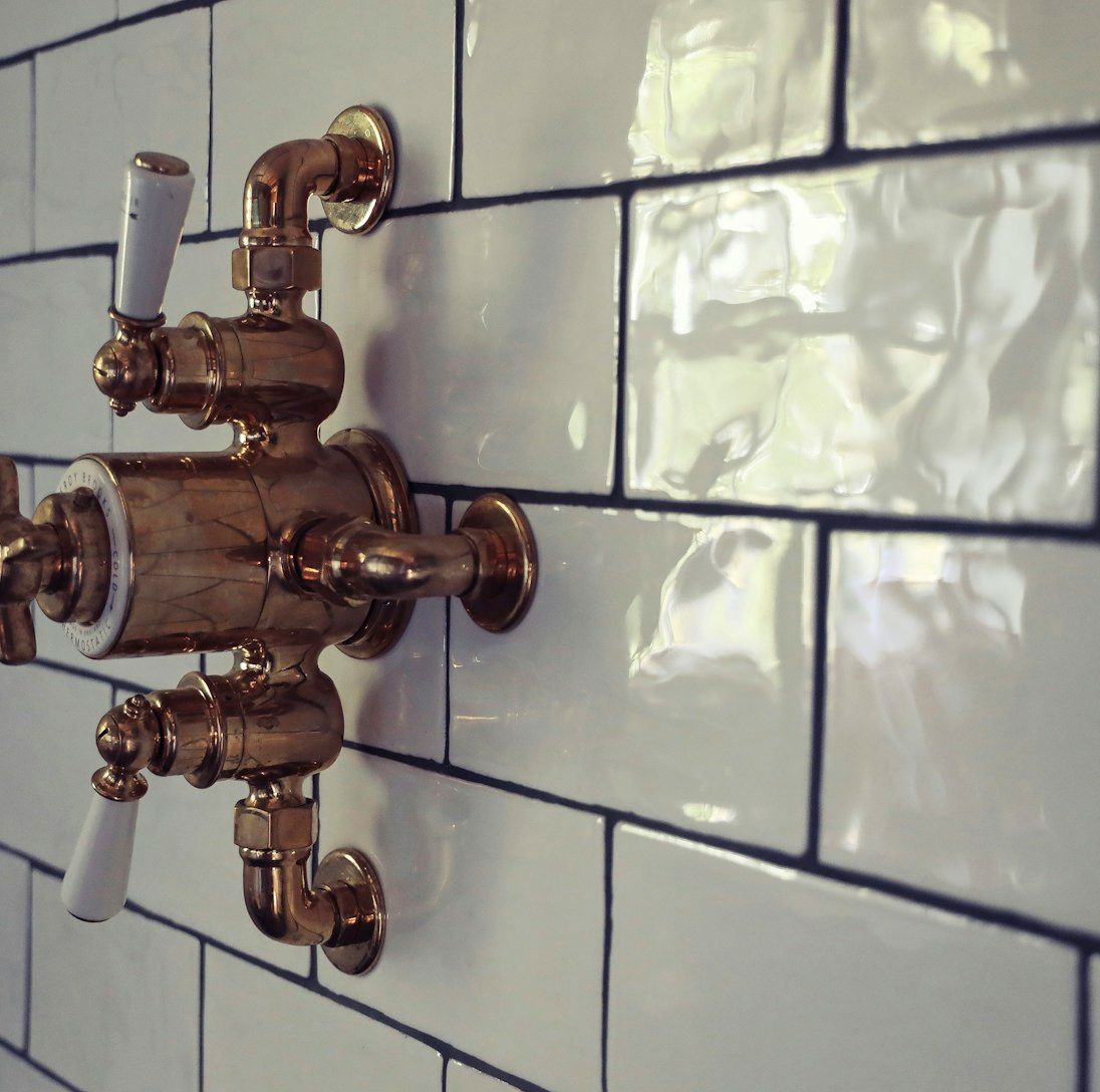 Gold shower fixtures on white tiled wall.
