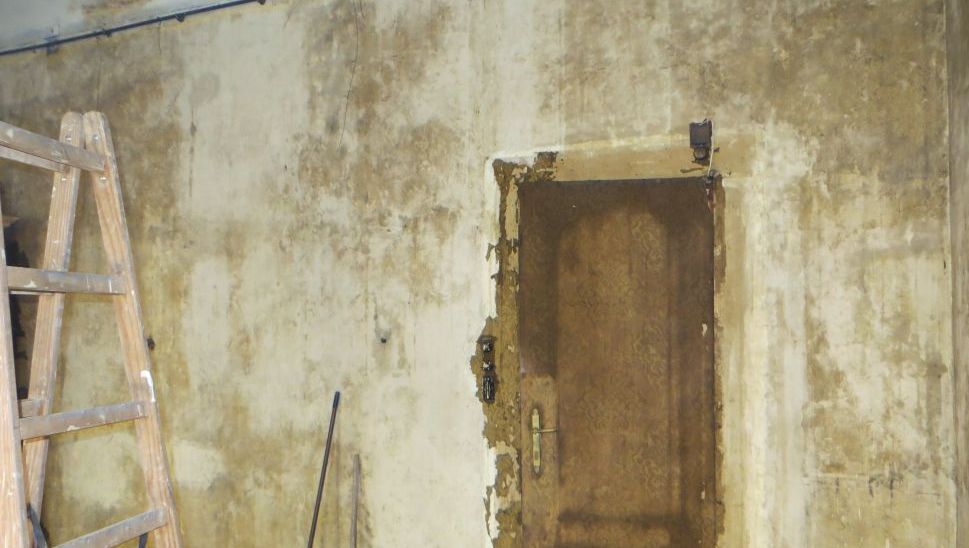 Eine Holzleiter steht neben einer Tür in einem Raum.