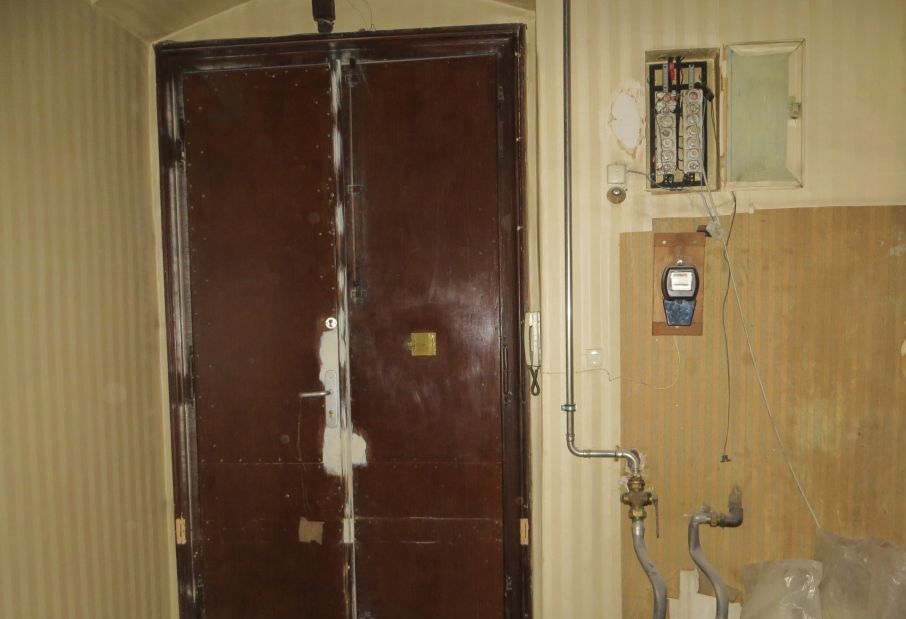 Ein Raum mit einer Tür und einem Telefon an der Wand.