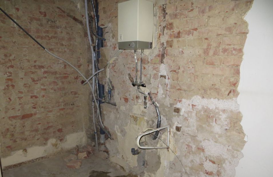 Ein Raum mit einer Ziegelwand und einem Warmwasserbereiter an der Wand.