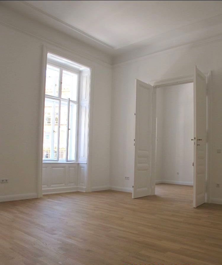 Ein renovierter Raum mit Hartholzböden und weißen Wänden