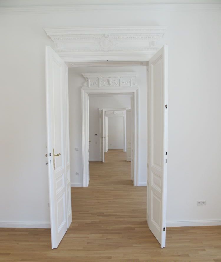 Ein leerer Flur mit weißen Wänden und Holzböden