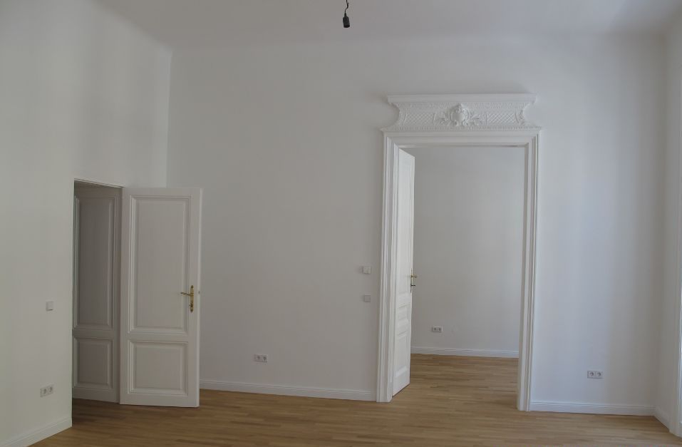 Ein leerer Raum mit weißen Wänden und Holzboden.