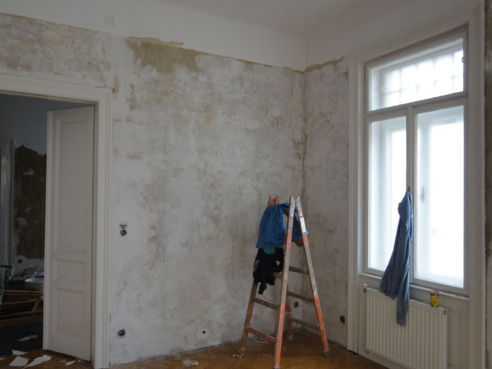 Ein leerer Raum mit einer Leiter in der Ecke und einem Fenster.