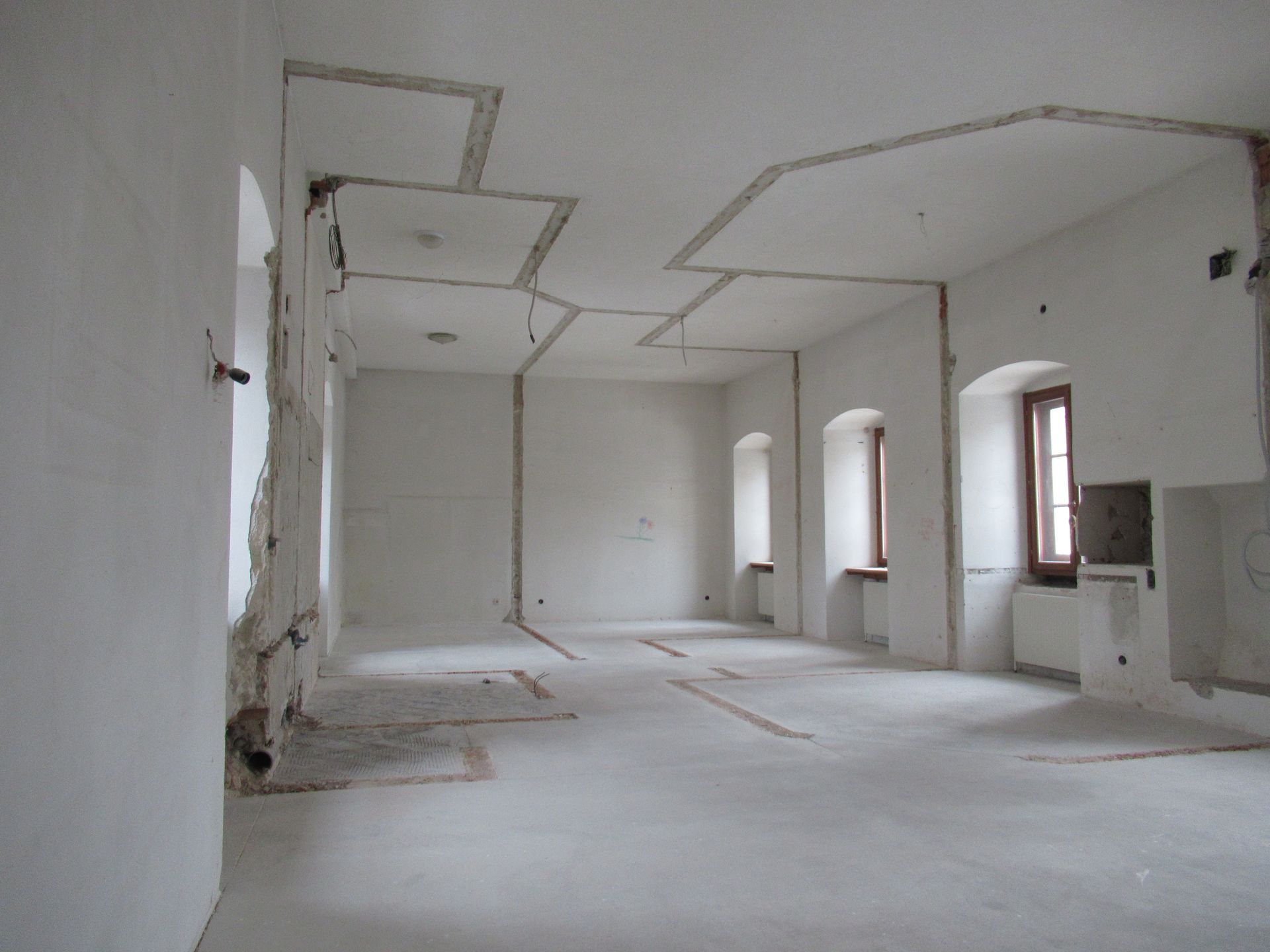 Ein leerer Raum mit weißen Wänden und ein paar Fenstern