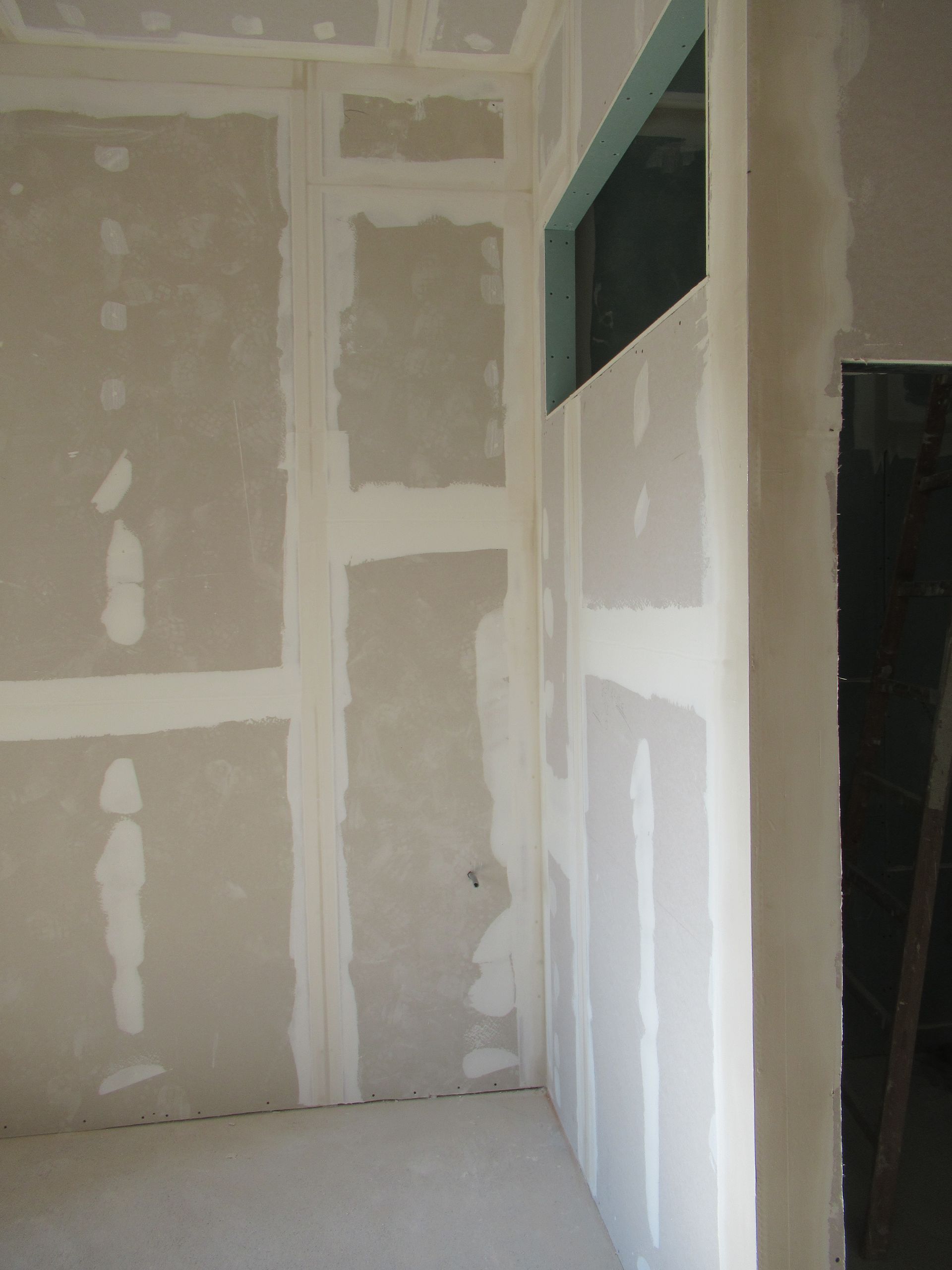 Ein Raum mit Gipskartonwänden und einem Fenster in der Ecke.