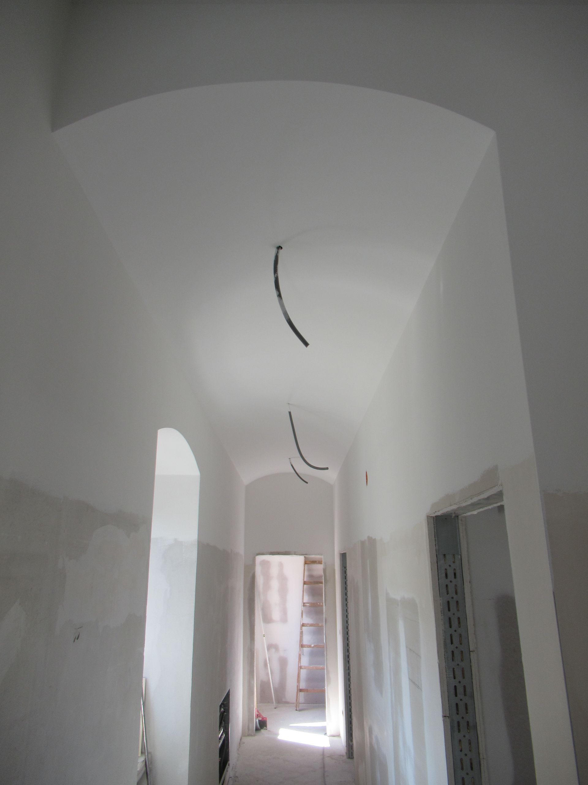 Ein langer Flur mit weißen Wänden und einer Decke, von der Kabel hängen.