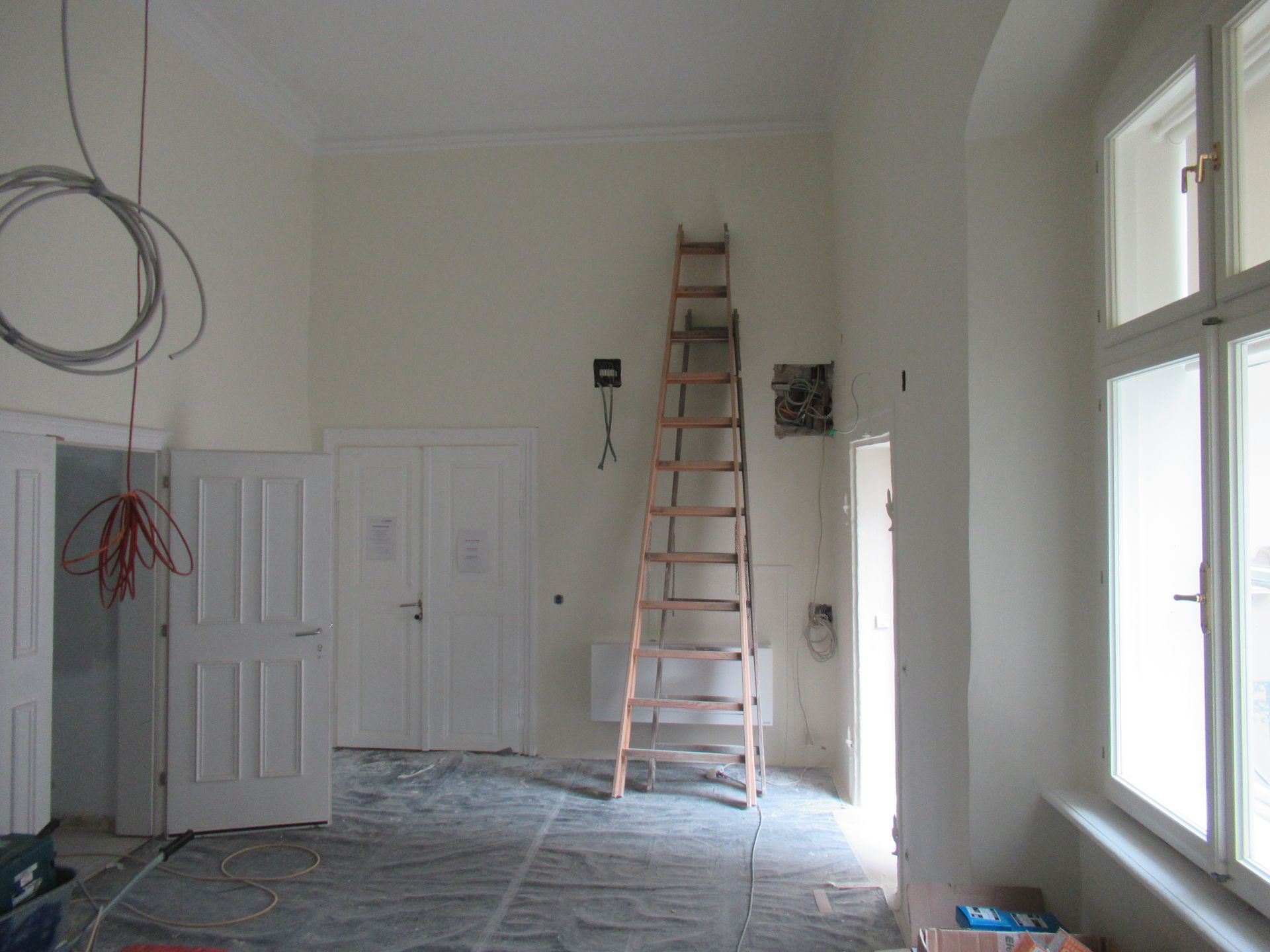 In der Mitte eines Raumes steht eine Holzleiter.