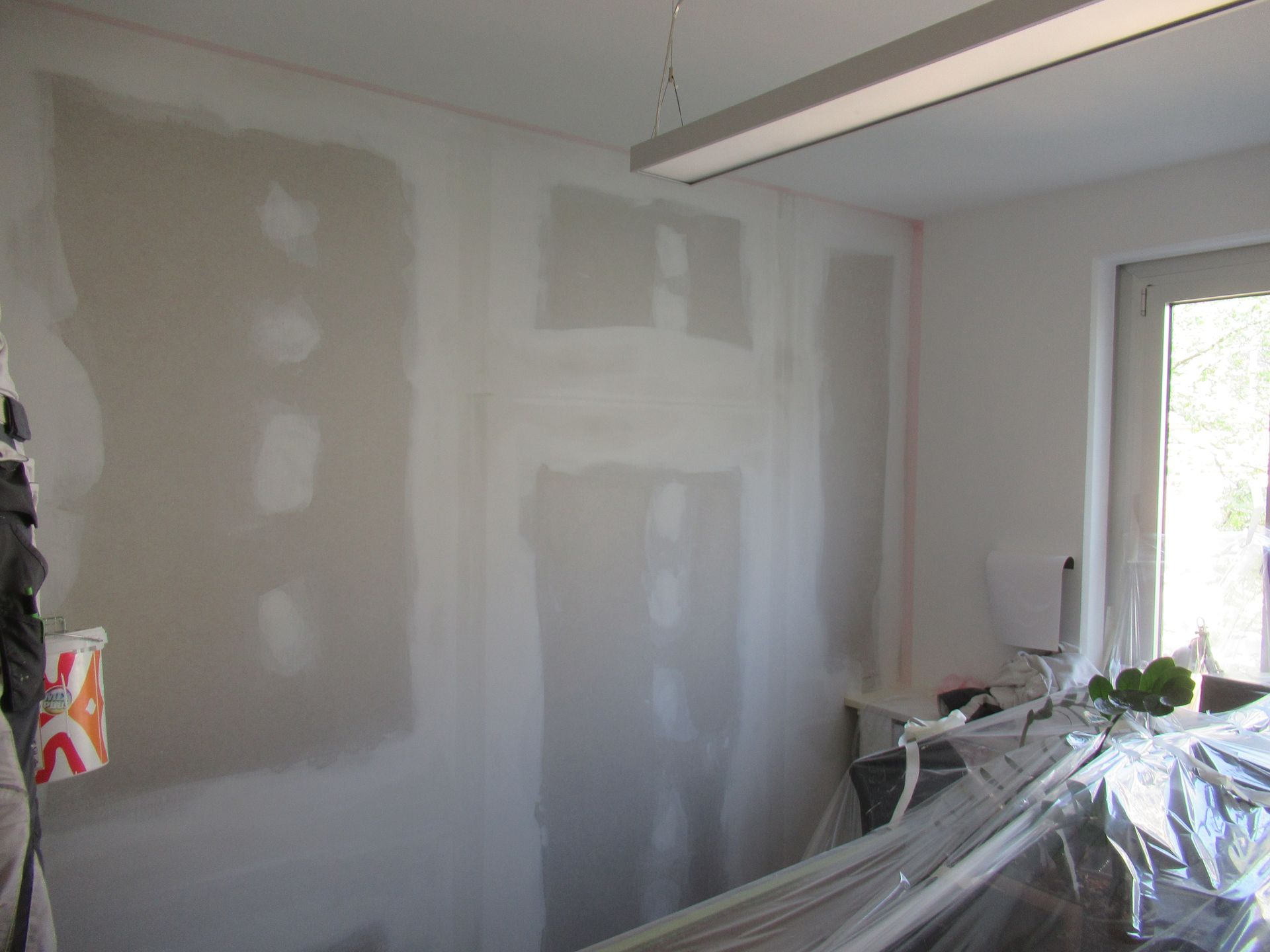 Eine Person streicht eine Wand in einem Raum mit einem Fenster.