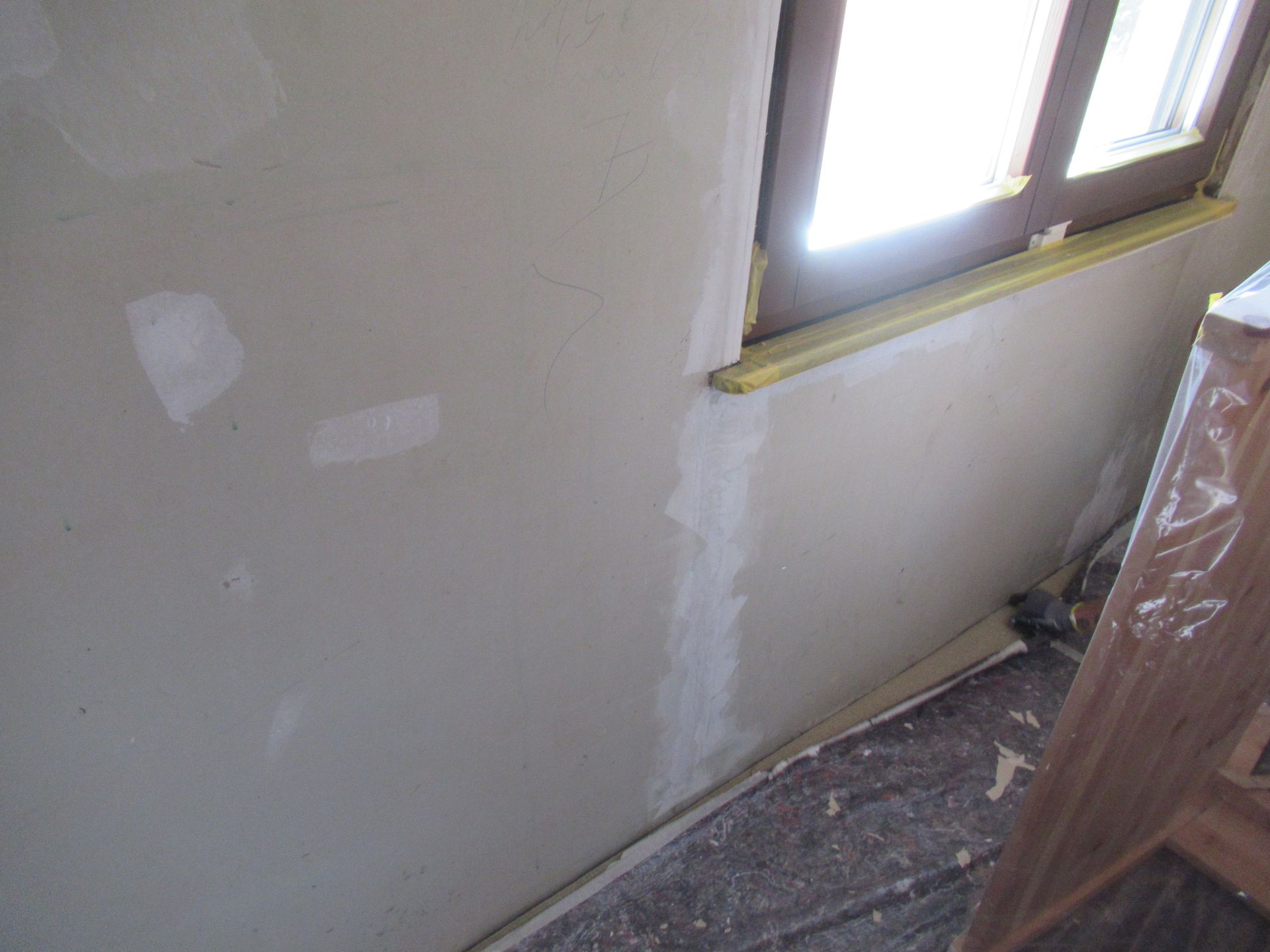 Eine weiße Wand mit einem Fenster in einem im Bau befindlichen Raum.