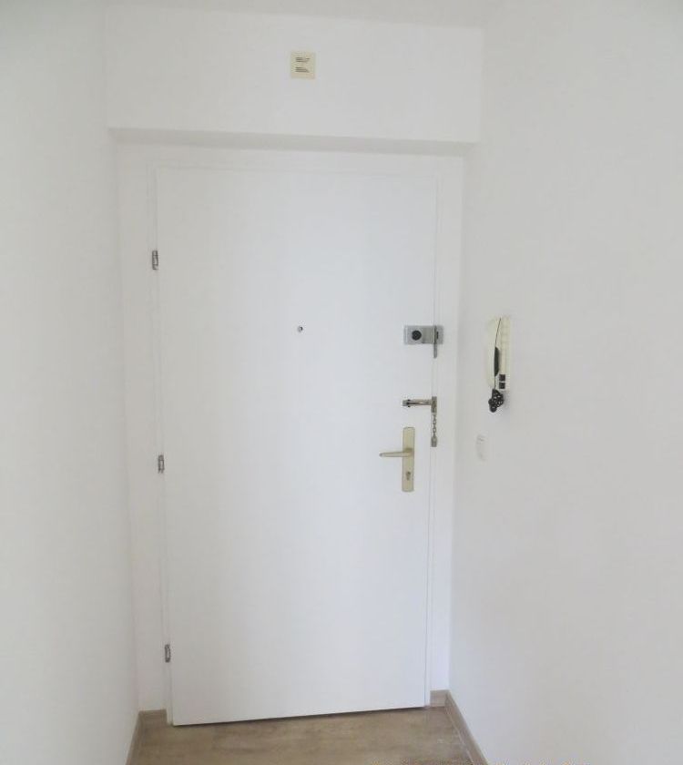 Ein leerer Flur mit einer weißen Tür und einem Telefon an der Wand.