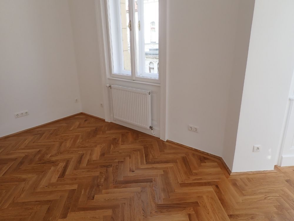 Ein leerer Raum mit Holzboden und Fenster.