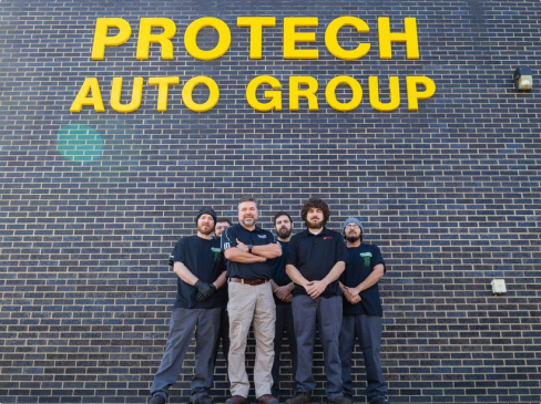 A group of men standing in front of a protech auto group sign  | Protech Auto Group Auto Repair