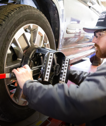 A man is working on a car wheel with a tool | Protech Auto Group Inc