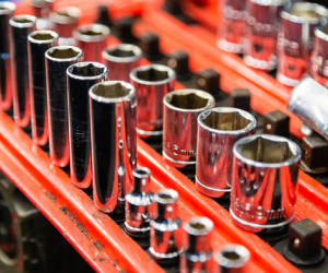 A row of chrome wrenches are lined up on a red shelf. | Protech Auto Group Inc