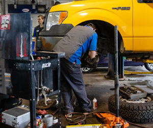 Our Mechanic is Working on a Yellow Truck in Our Garage - Protech Auto Group Inc.