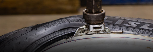 A close up of a tire being repaired with a wrench.  | Protech Auto Group Auto Repair