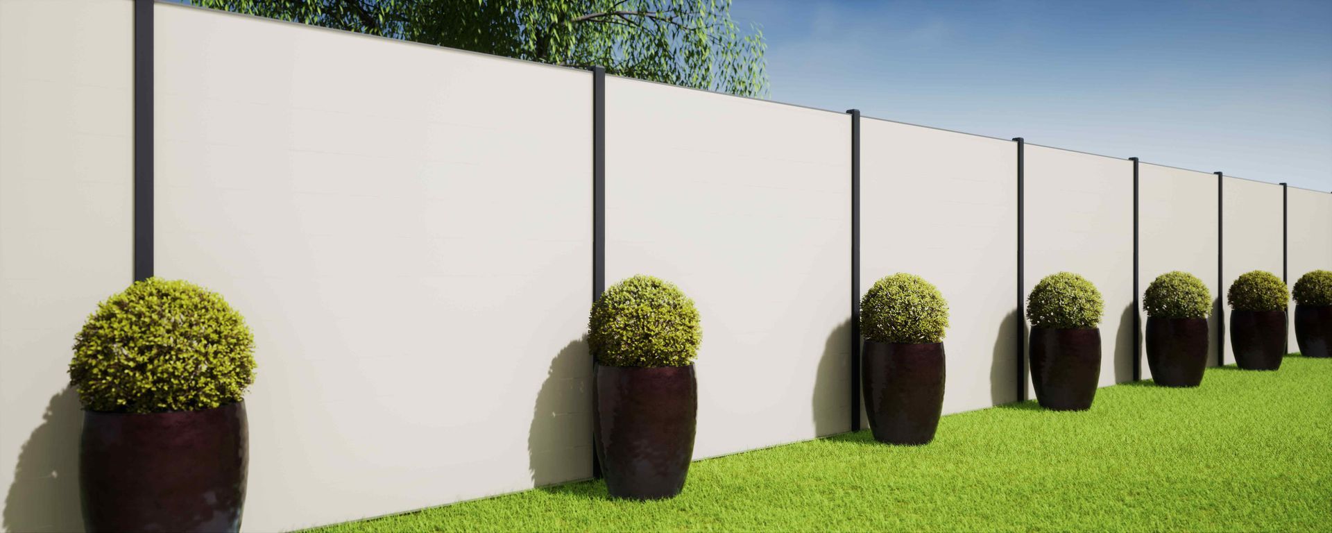 White fence with black poles, potted shrubs, and green grass. Blue sky in background.