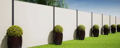 Row of black planters with round green shrubs along a white fence beside a grassy lawn