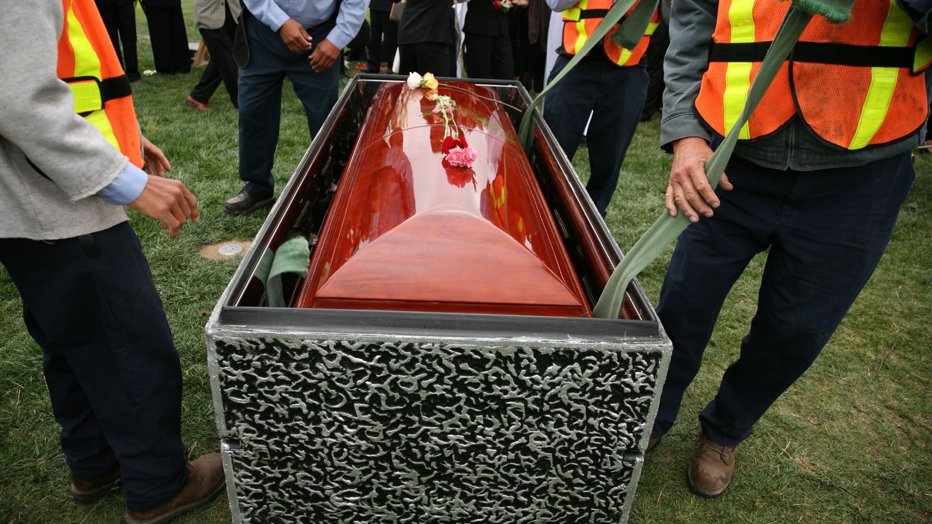 group of people laying a casket into the ground