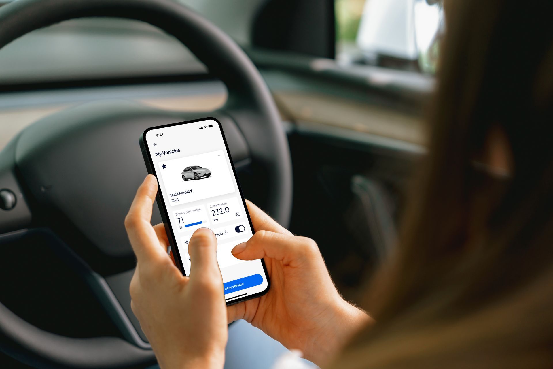 Man sluit een elektrische autolader aan op een grijze auto die op straat geparkeerd staat. 