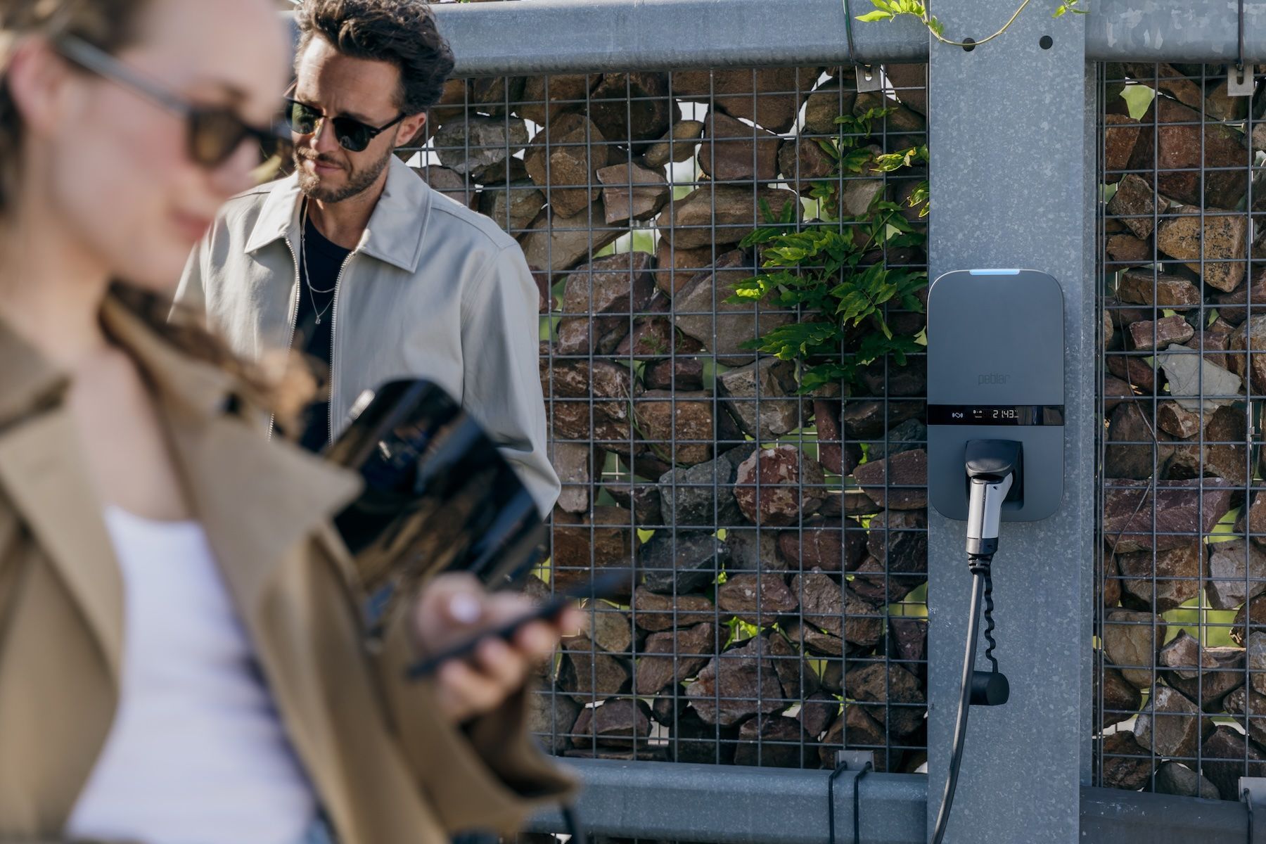 Man met sleutelhanger bij een witte elektrische auto die wordt opgeladen.