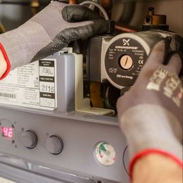 a person wearing gloves is working on a grundfos pump