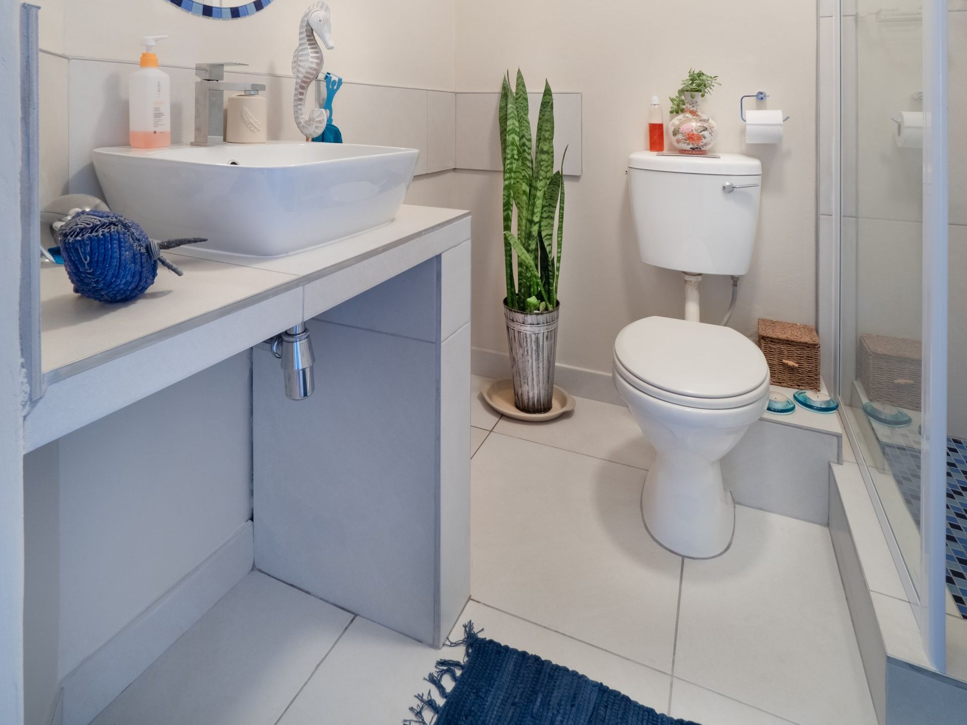 a bathroom with a toilet a sink and a plant