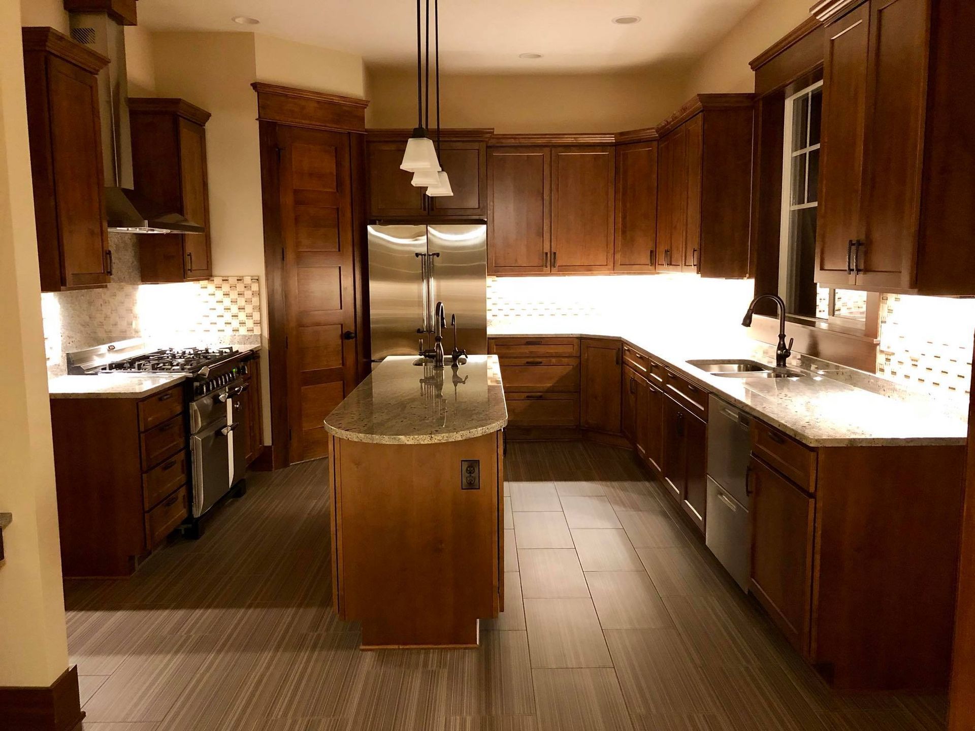 A kitchen with dark wood cabinets, a stainless steel refrigerator, and a center island with a granite countertop.