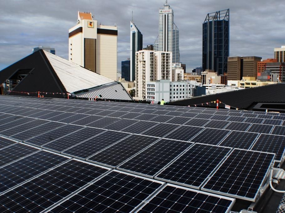 Solar panels on the roof of a building with a city skyline in the background