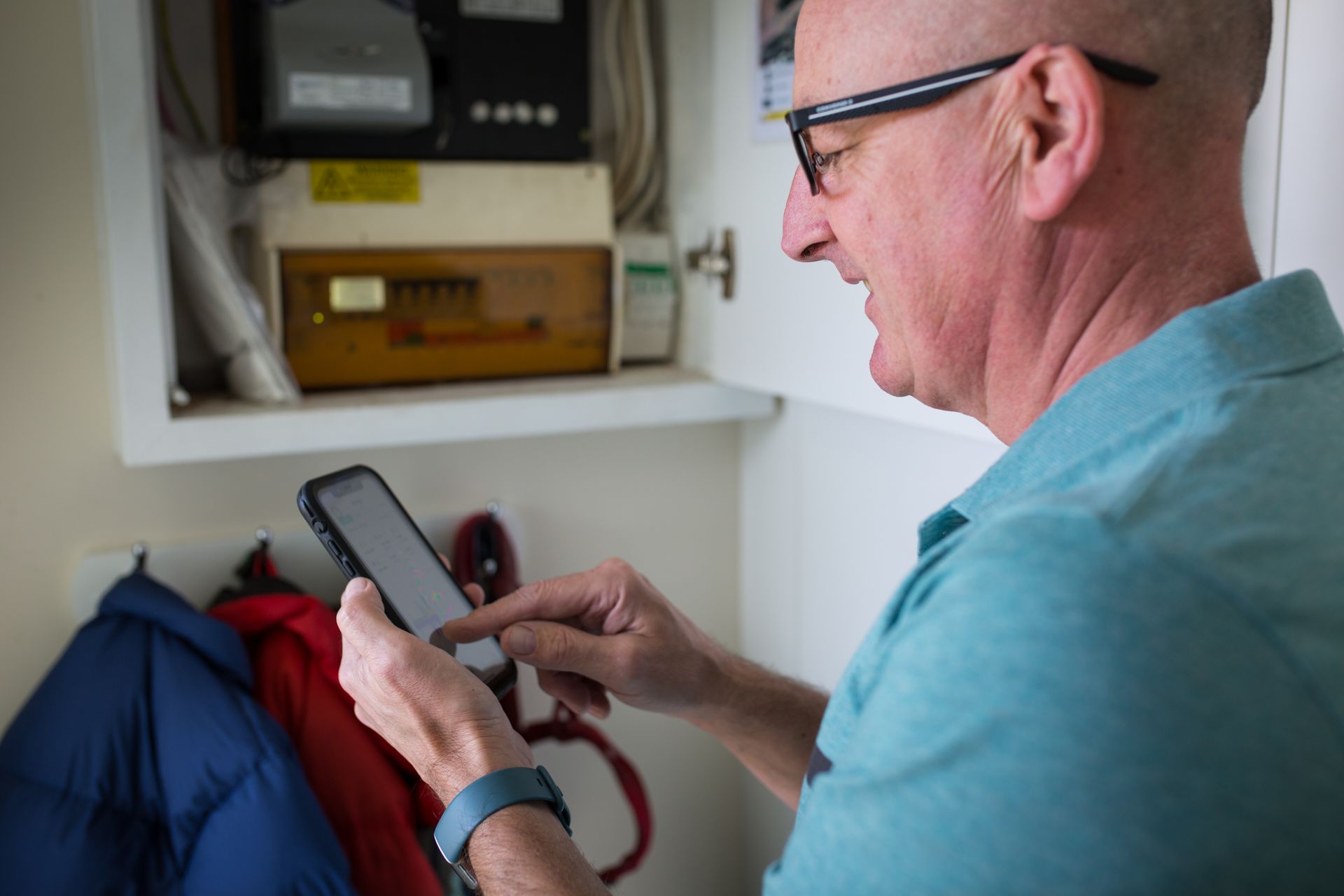A man is looking at a cell phone in a cabinet.