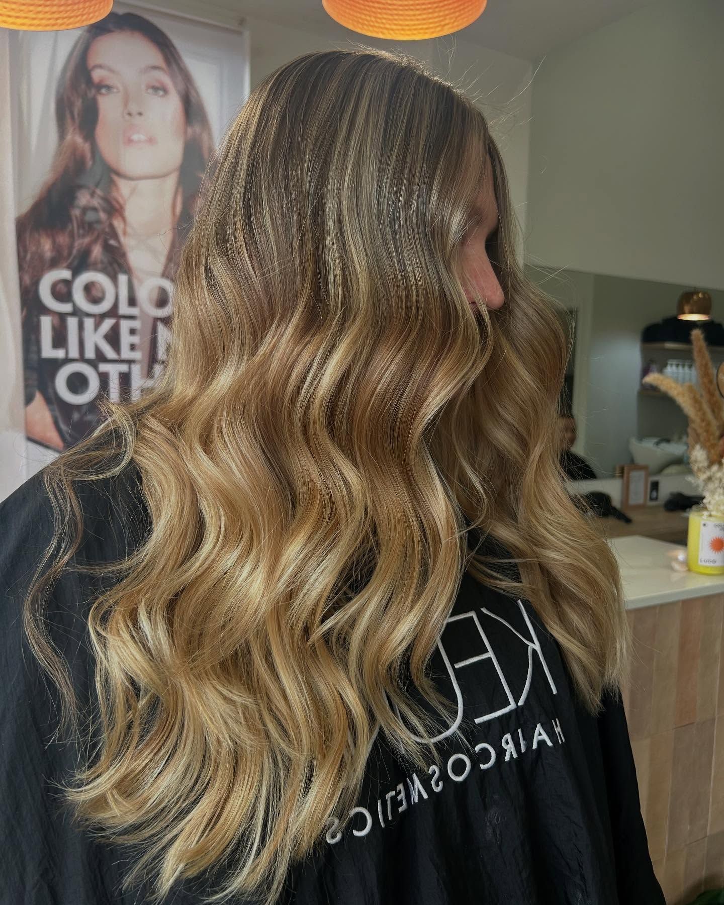A Woman With Long Blonde Hair Is Standing In Front Of A Sign — Hair By Jell In Cannonvale, QLD