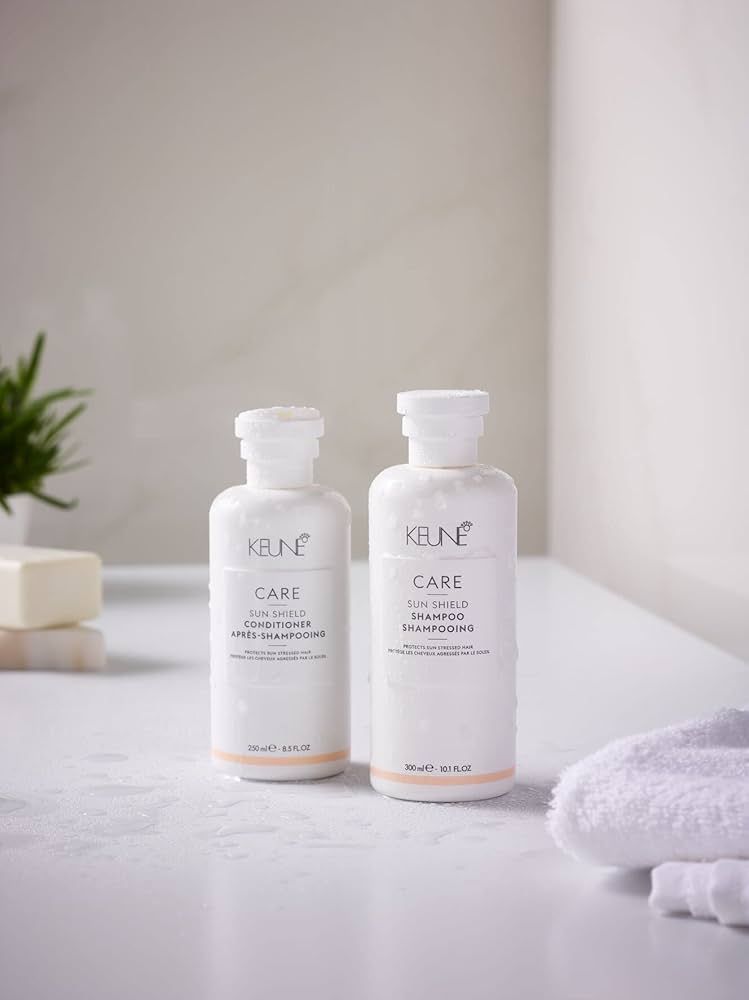 Two Bottles of Hair Products Are Sitting on a Table Next to a Vase of Flowers — Hair By Jell In Cannonvale, QLD