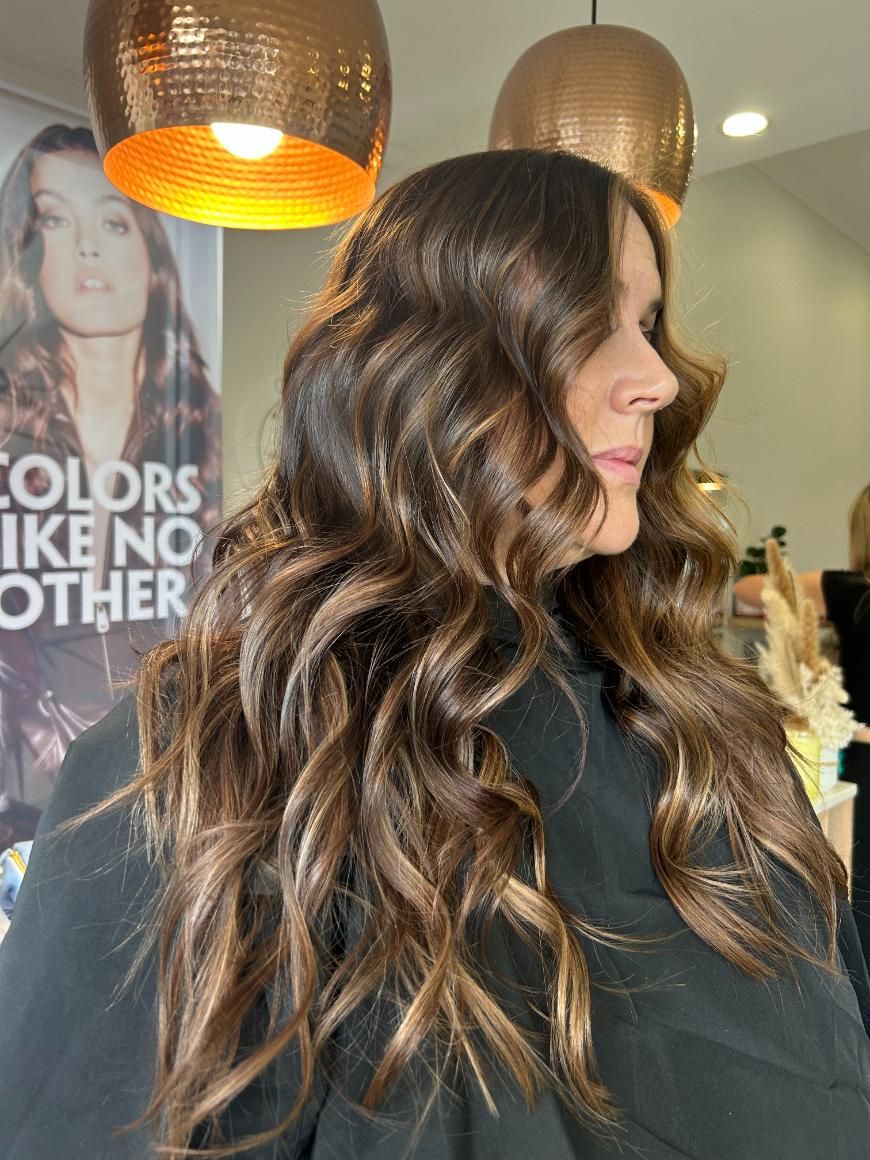 A Woman With Long Brown Hair is Sitting in a Salon — Hair By Jell In Cannonvale, QLD