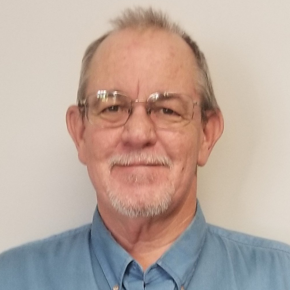 A man with glasses and a beard is wearing a blue shirt