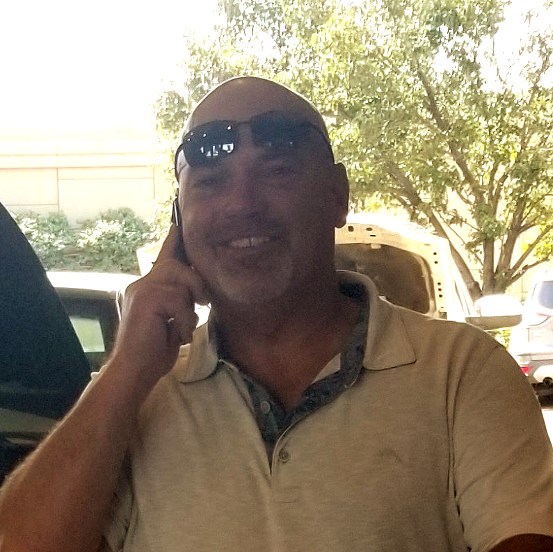 A man wearing sunglasses is talking on a cell phone