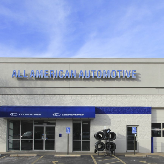 The front of an all american automotive store with a blue awning