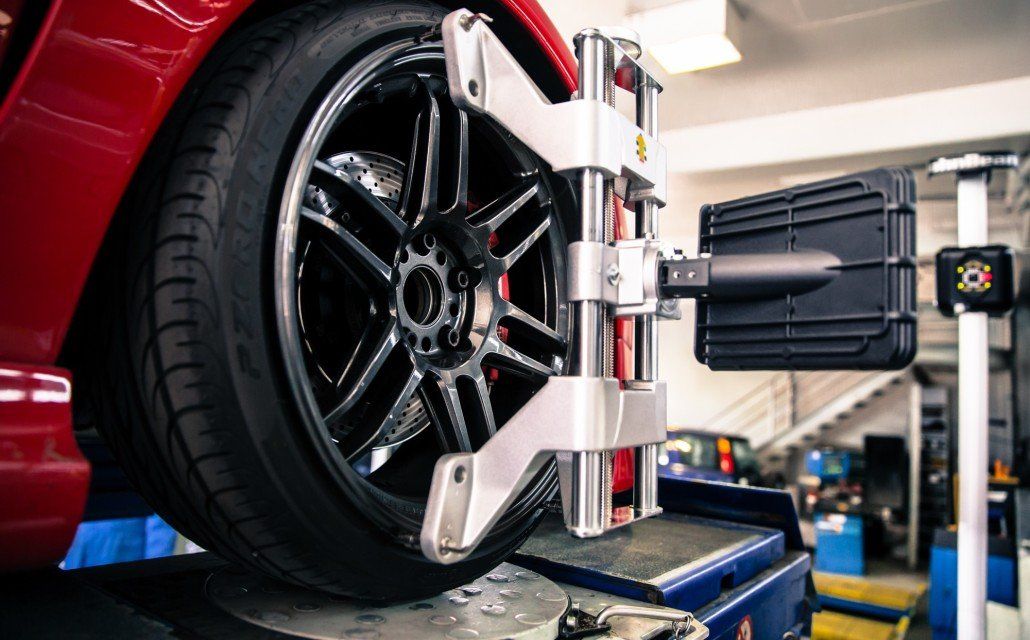 A red car is being adjusted by a machine in a garage.