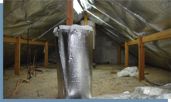 An attic with a pipe covered in aluminum foil