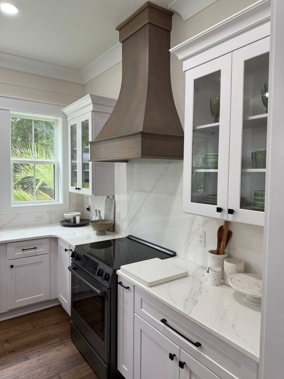 A kitchen with white cabinets and wooden counter tops and a sink.