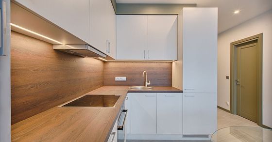 A kitchen with white cabinets and wooden counter tops and a sink.