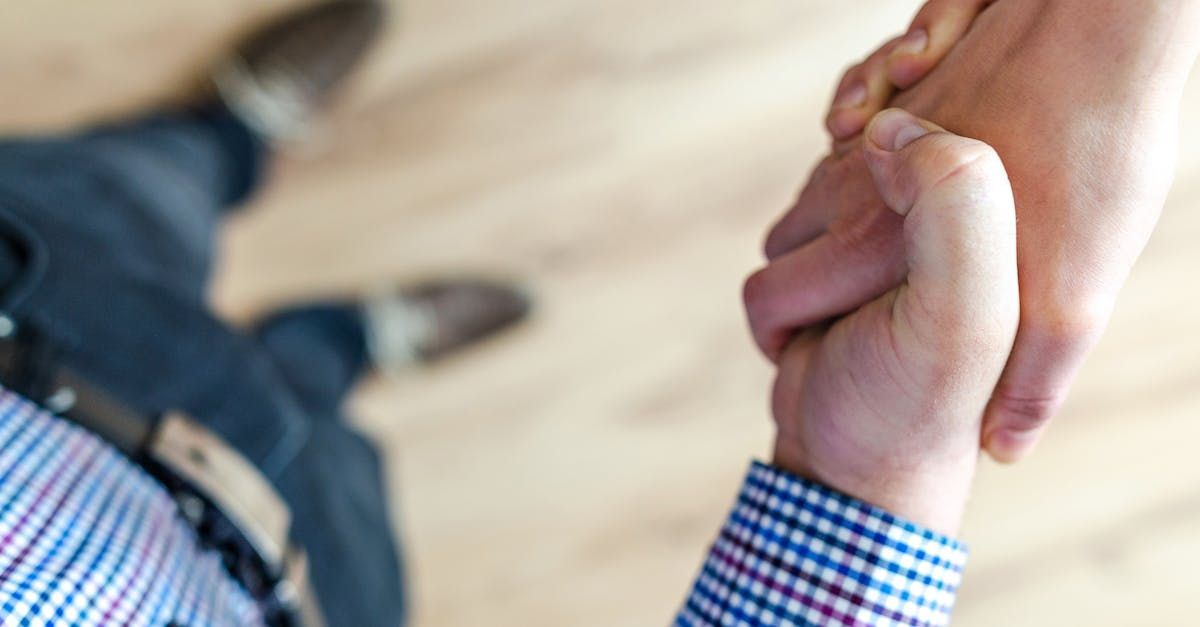 Two people are shaking hands on a wooden floor.