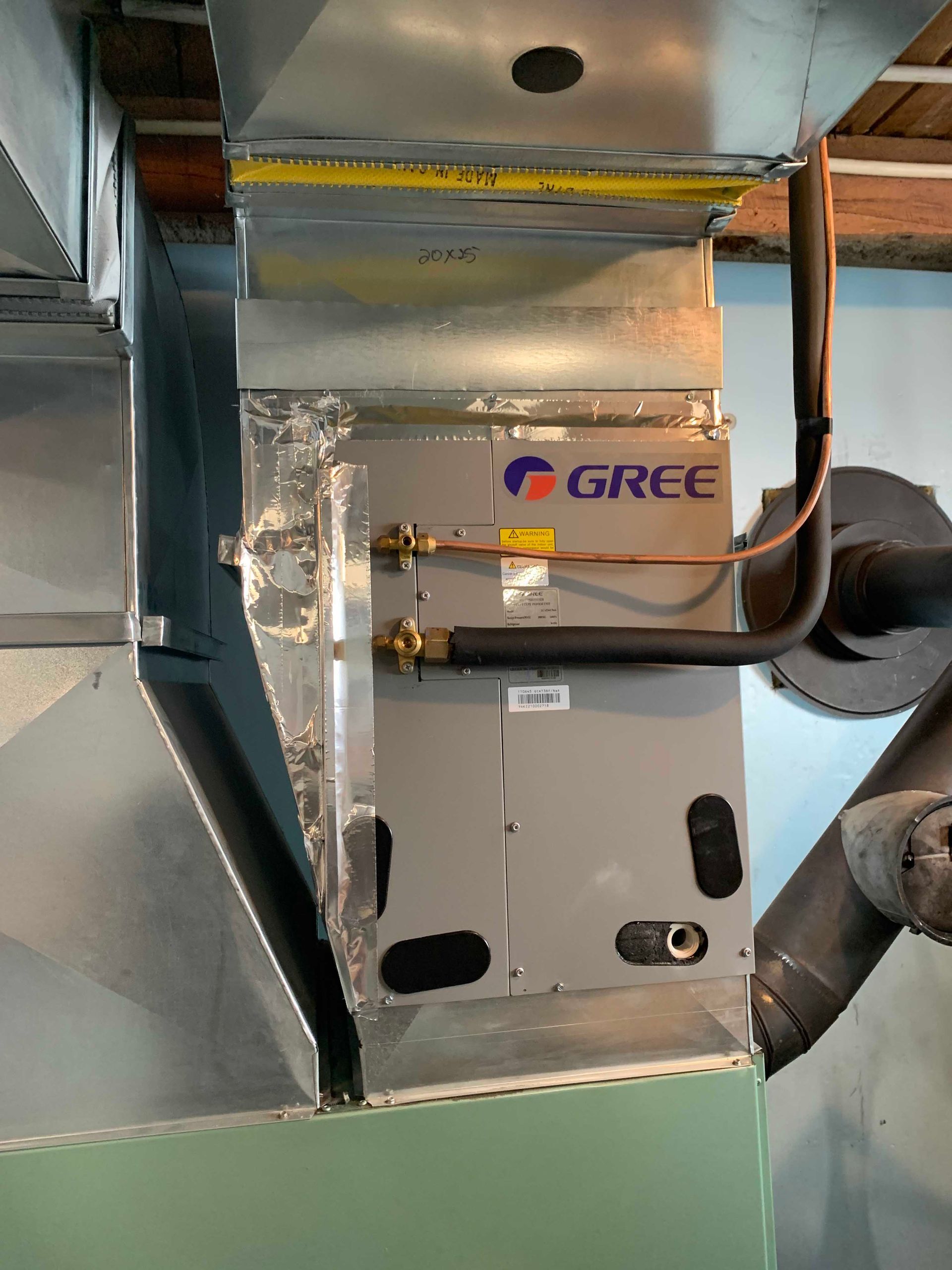 Unité de traitement d'air GREE installée dans un réseau de conduits avec des tubes en cuivre et des conduites de réfrigérant.