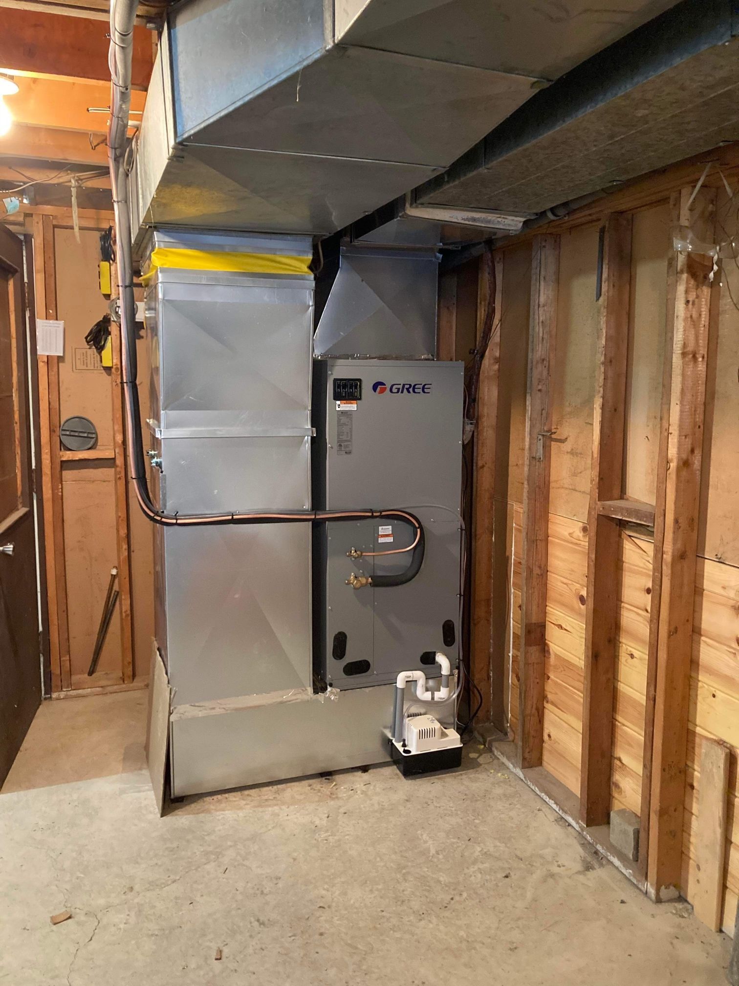 Système de chauffage, ventilation et climatisation installé au sous-sol, avec conduits et pompe. Tons gris et argentés.