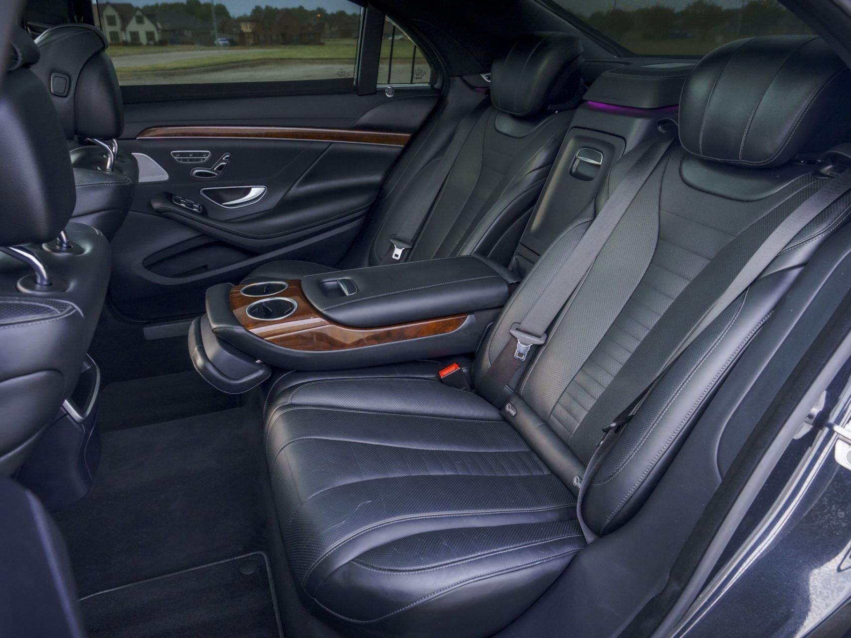 Interior of a bus, red and black seats line the aisle. Wooden floor, red ceiling.