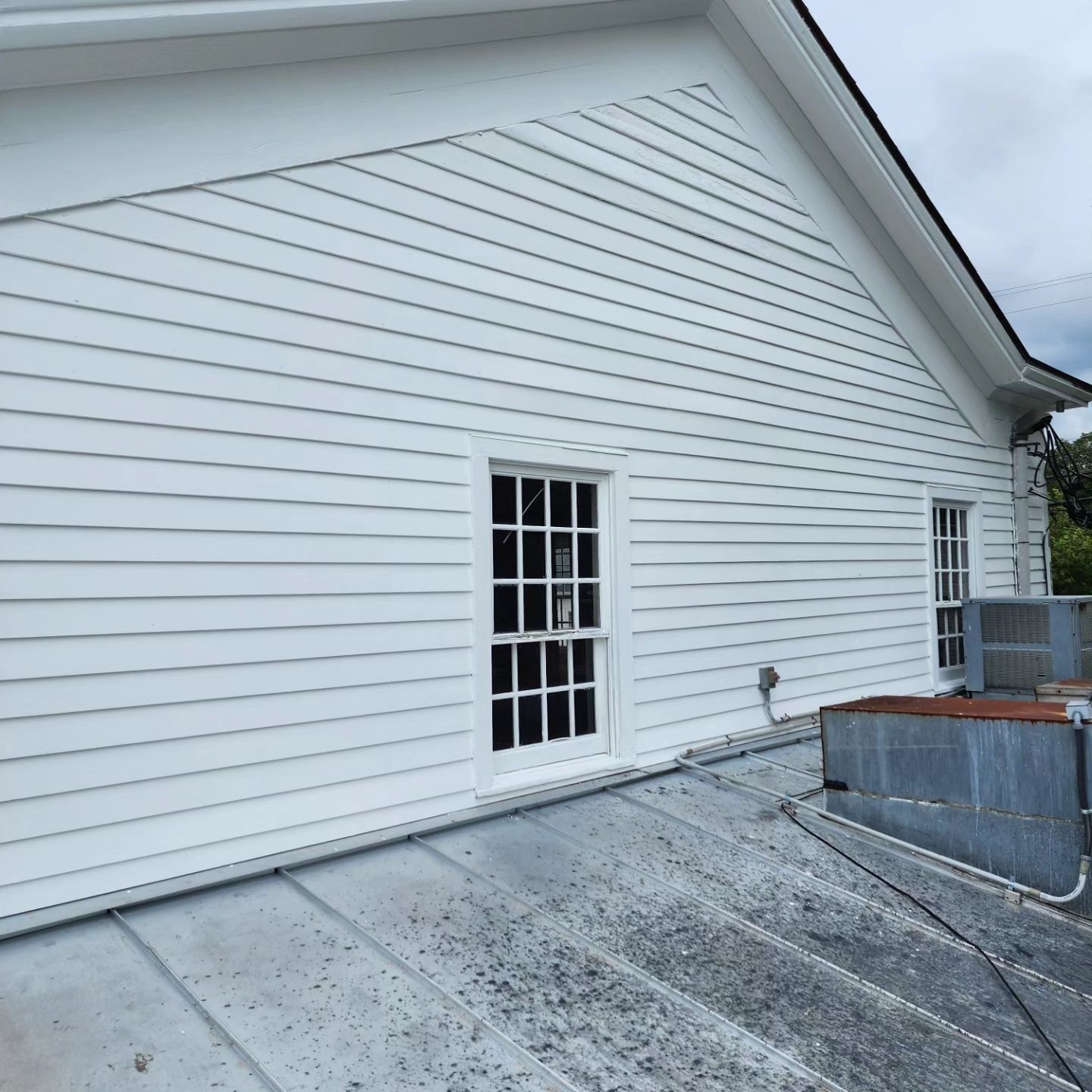 White siding and windows on a building with a metal roof.